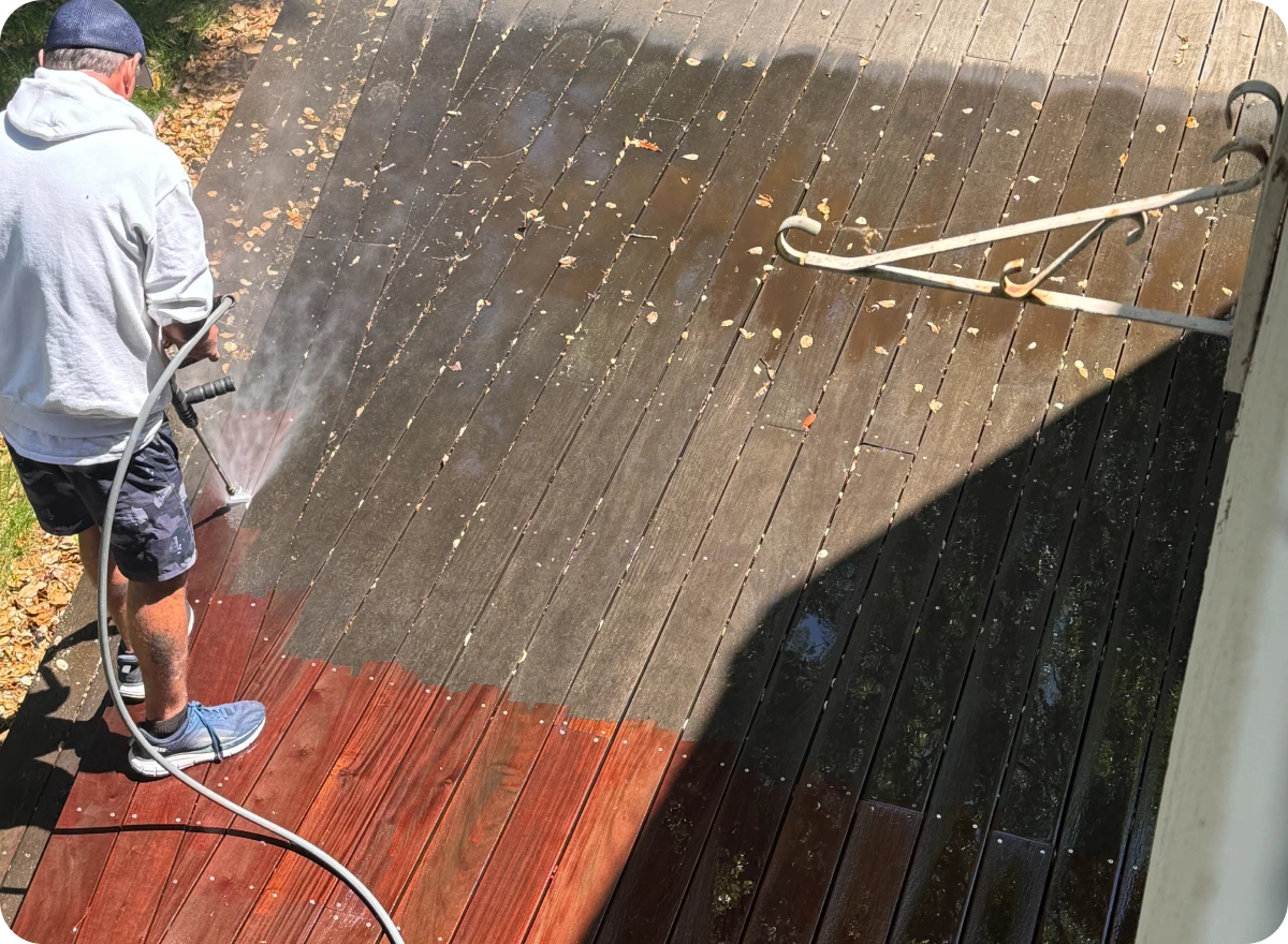 Man pressure washing a wooden deck.