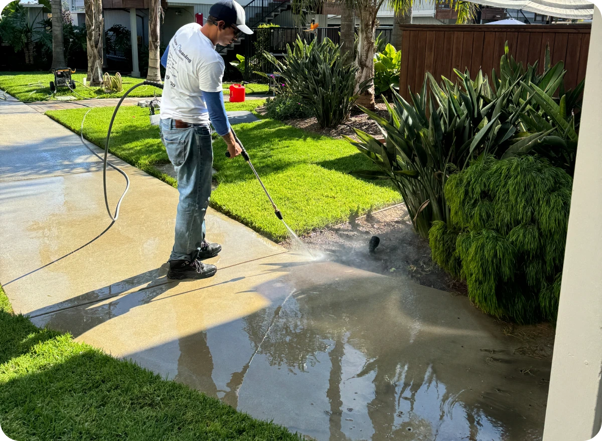 Man pressure washing a concrete driveway.