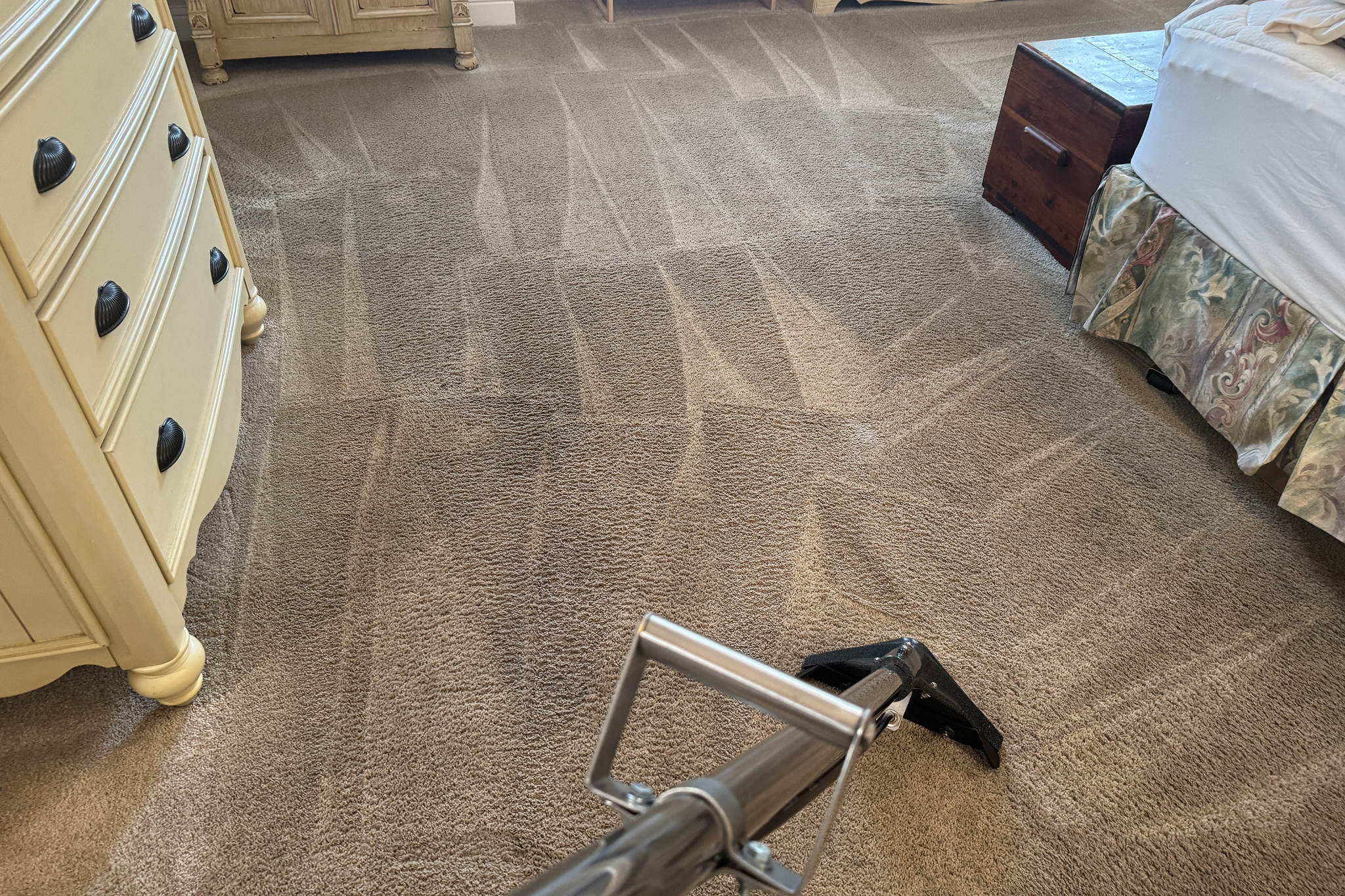 Vacuuming carpet in a tidy bedroom.