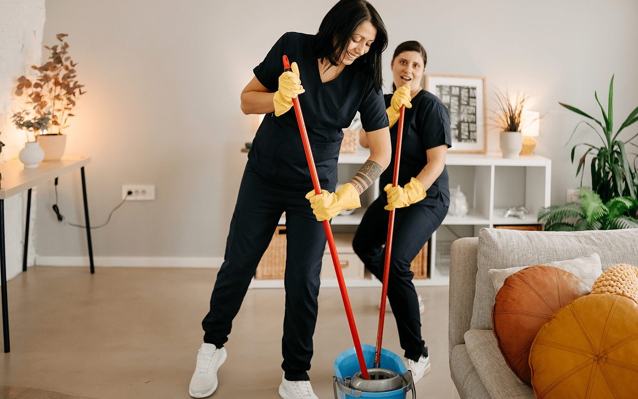 Two women mopping a modern living room.
