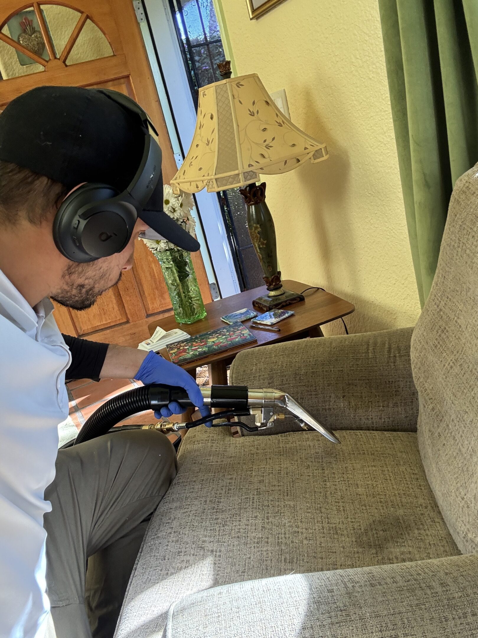 Person cleaning sofa with vacuum tool.