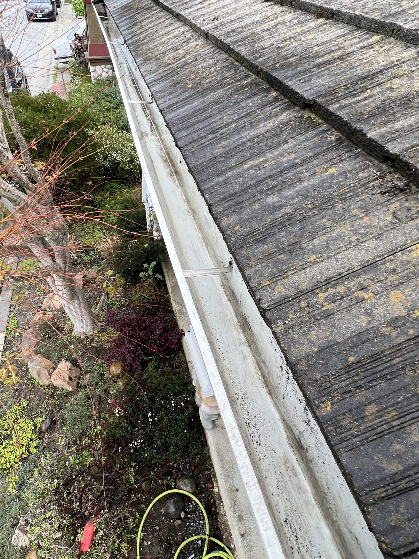 Dirty roof and gutter with garden below.