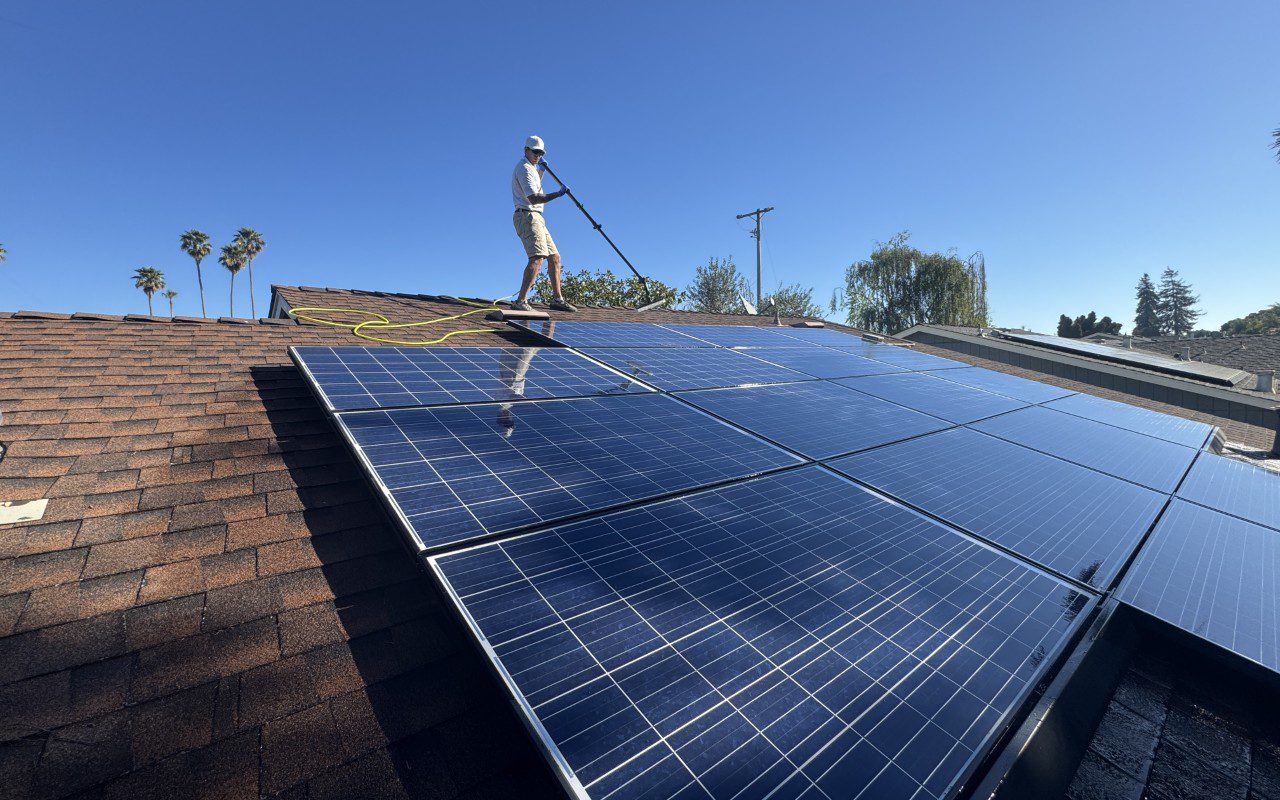 Person cleaning solar panels on rooftop.