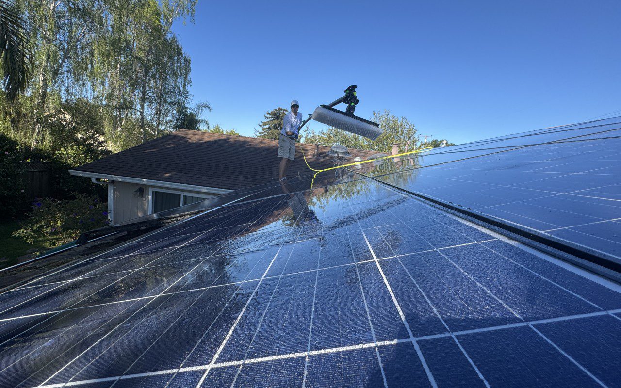 Man cleaning solar panels on rooftop.