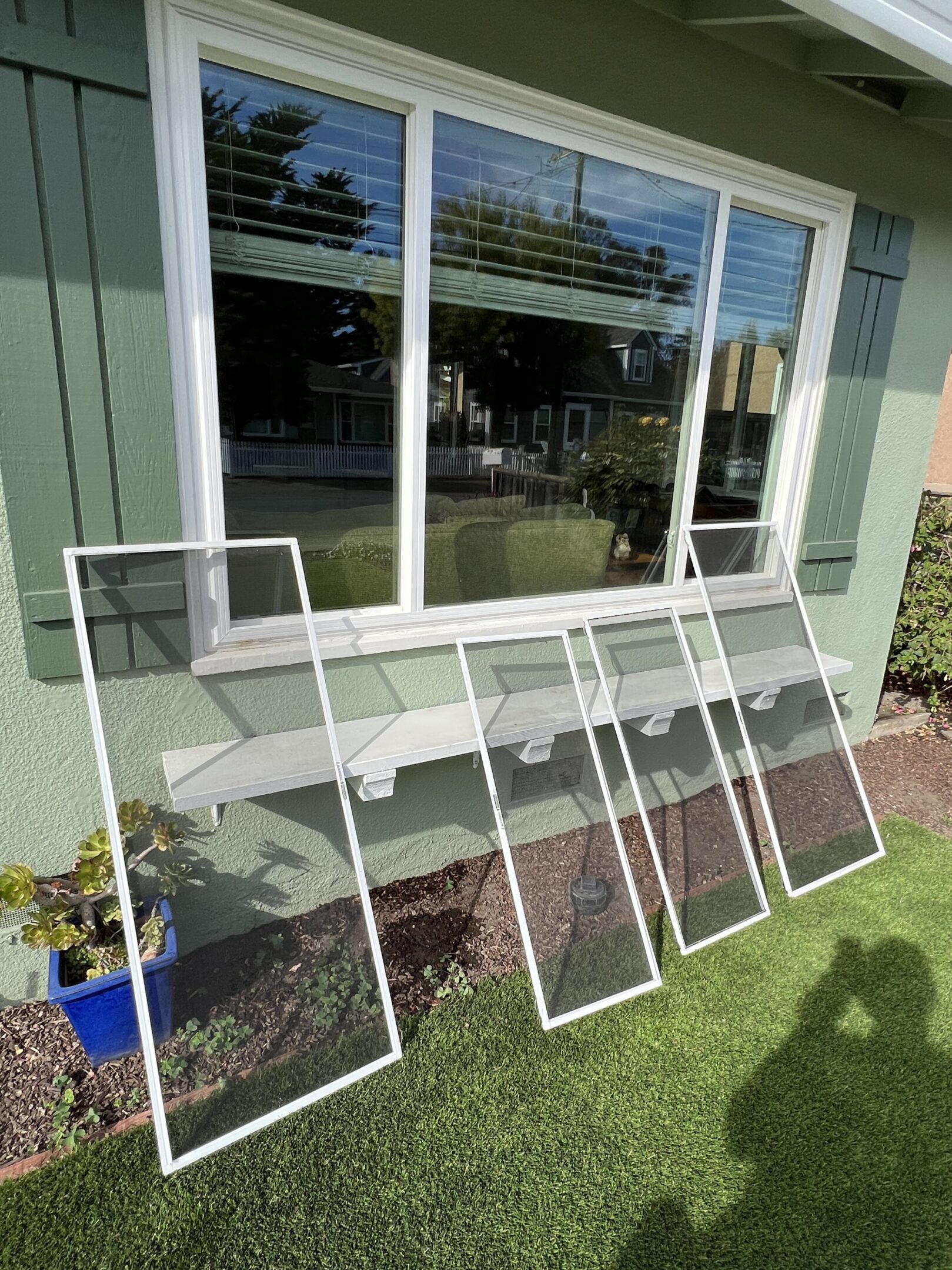 Window screens leaning against house wall.