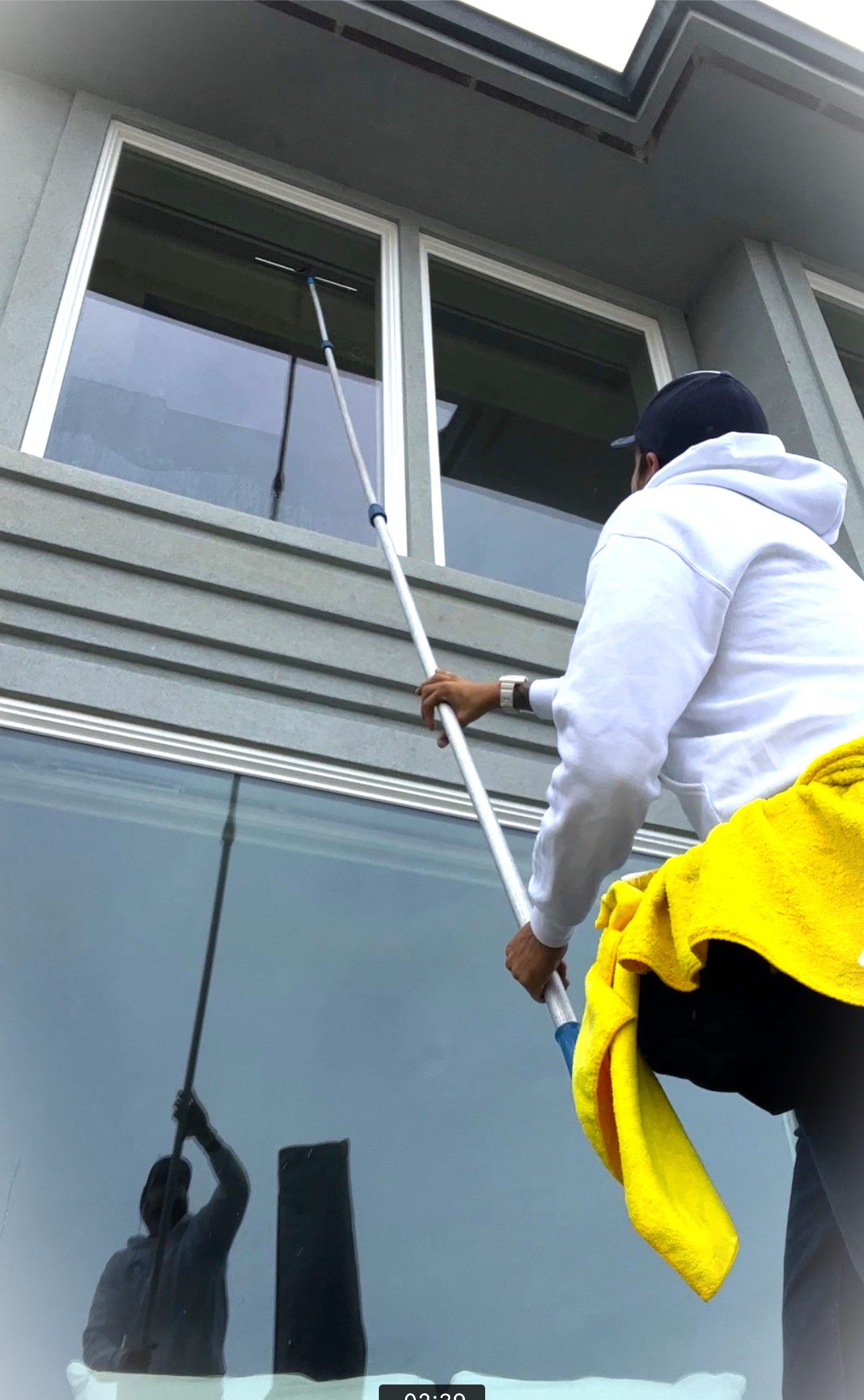Person cleaning windows with an extendable pole.