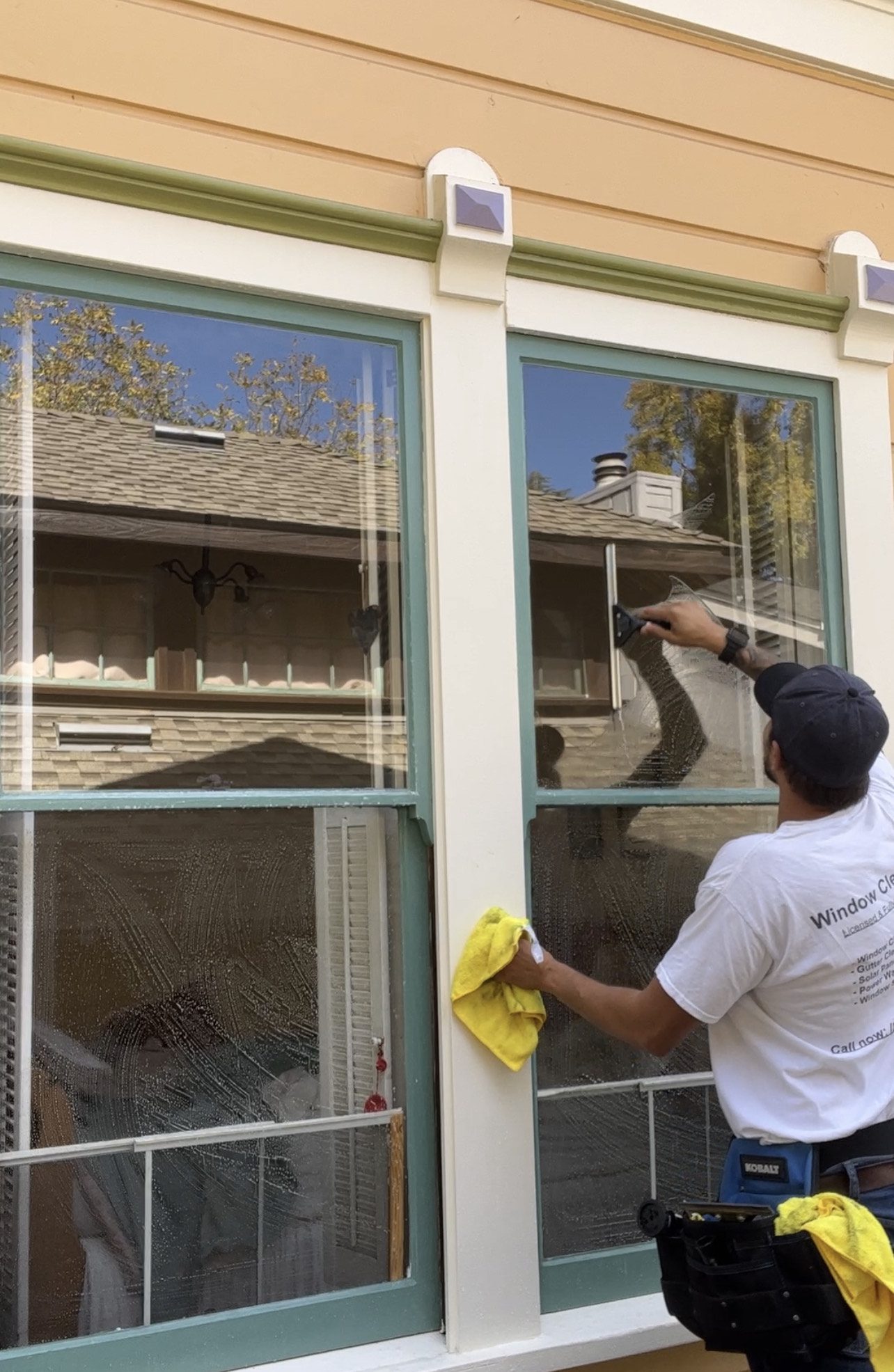 Man cleaning large glass windows with squeegee.
